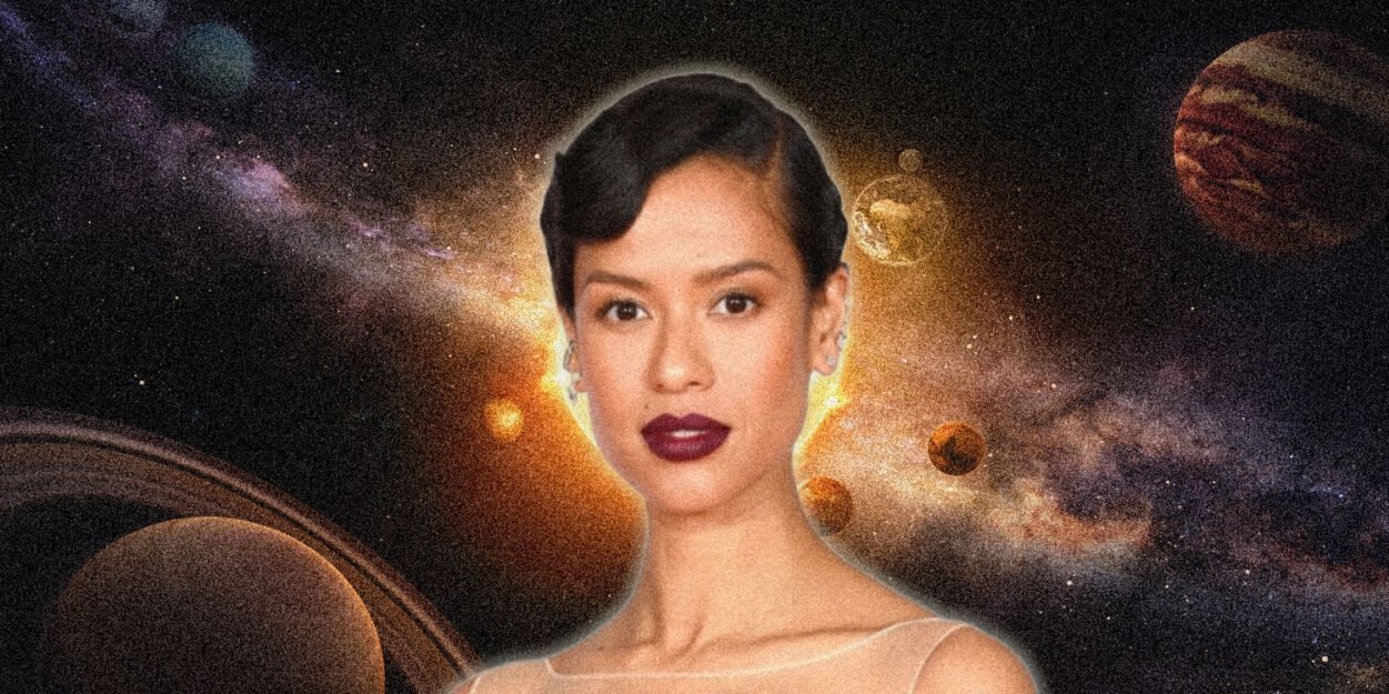 Portrait of a woman with short dark hair and bold lipstick, set against a cosmic space scene with planets and a glowing background.