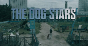 “THE DOG STARS” big title over a deserted city lot; a man walks a dog along a dirt path amid debris and fences.