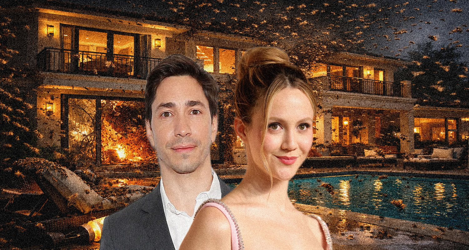 A man in a gray suit and a woman in a pink dress pose in front of a lit luxury house with a pool and falling leaves nearby.