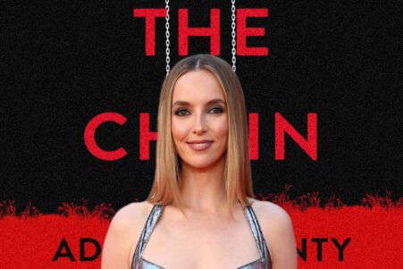 Portrait of a woman on the red carpet, standing in front of a black-and-red poster reading 'THE CHAIN' with hanging chains imagery.