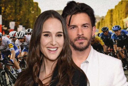 Smiling couple posing in front of a cycling race scene on the road with cyclists in motion behind them, crowding the background.