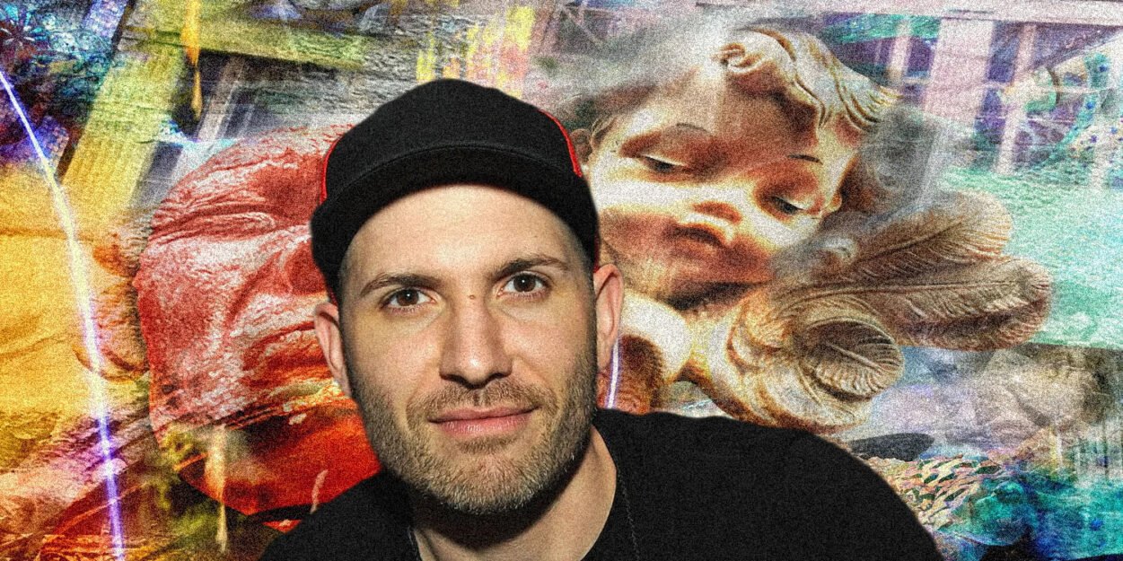Man wearing a black cap and dark shirt posing in front of a vibrant graffiti mural featuring a large sleeping cherub image.