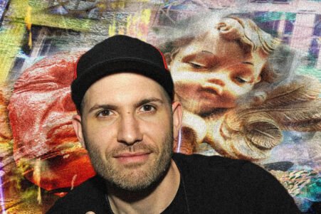Man wearing a black cap and dark shirt posing in front of a vibrant graffiti mural featuring a large sleeping cherub image.