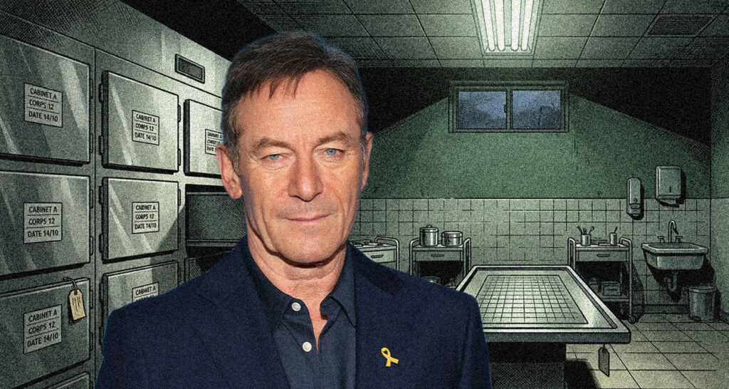 Man in a dark blazer with a yellow ribbon lapel pin stands in a vault-like room filled with metal safes and a large table in the background.