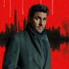Man in a dark gray overcoat and scarf poses in front of a red skyline with a black water-reflection scene behind him.