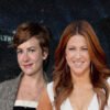 Two smiling women pose together at night in front of a Hollywood backdrop with city lights behind them at dusk.