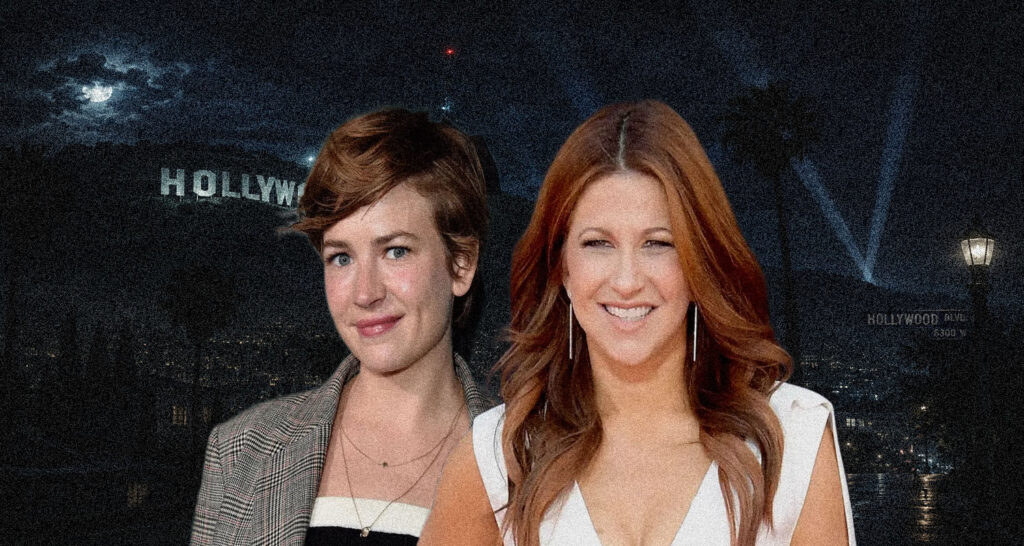Two smiling women pose together at night in front of a Hollywood backdrop with city lights behind them at dusk.