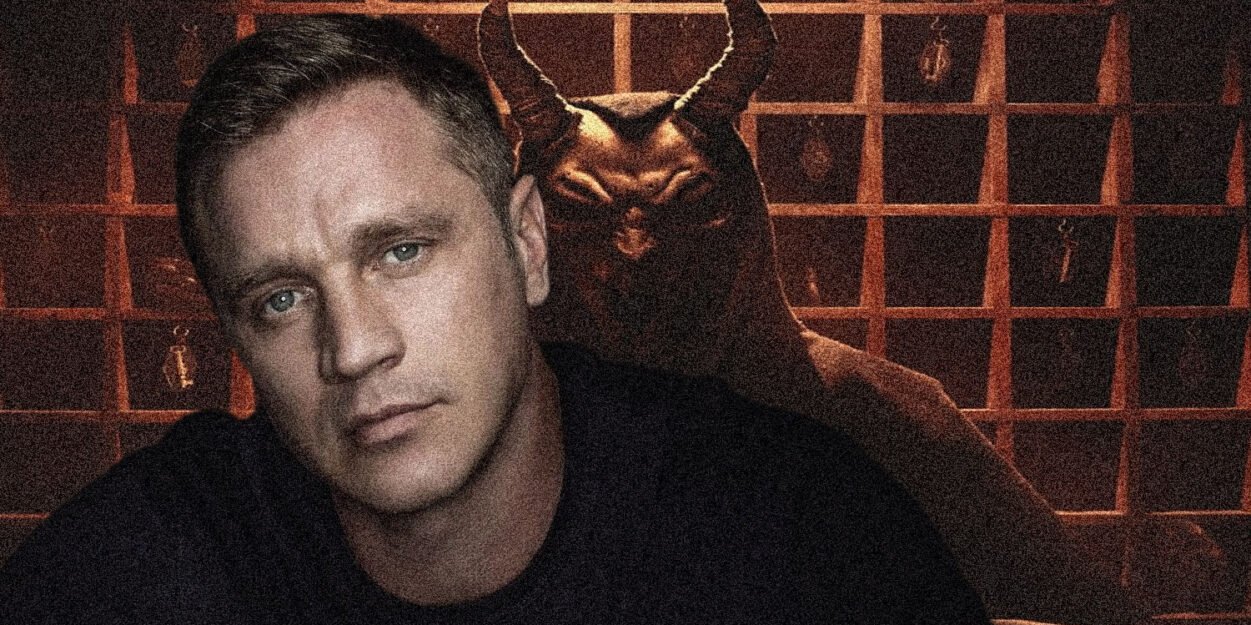 Moody portrait: man in foreground with pale skin, blue eyes, dark shirt; a horned demon figure looms behind him in a dim, grid-patterned background.