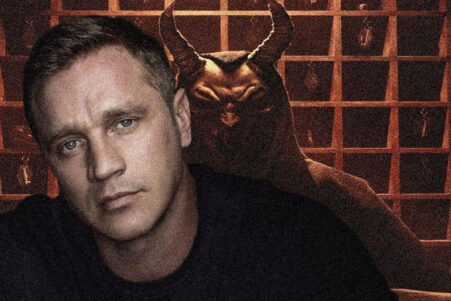 Moody portrait: man in foreground with pale skin, blue eyes, dark shirt; a horned demon figure looms behind him in a dim, grid-patterned background.