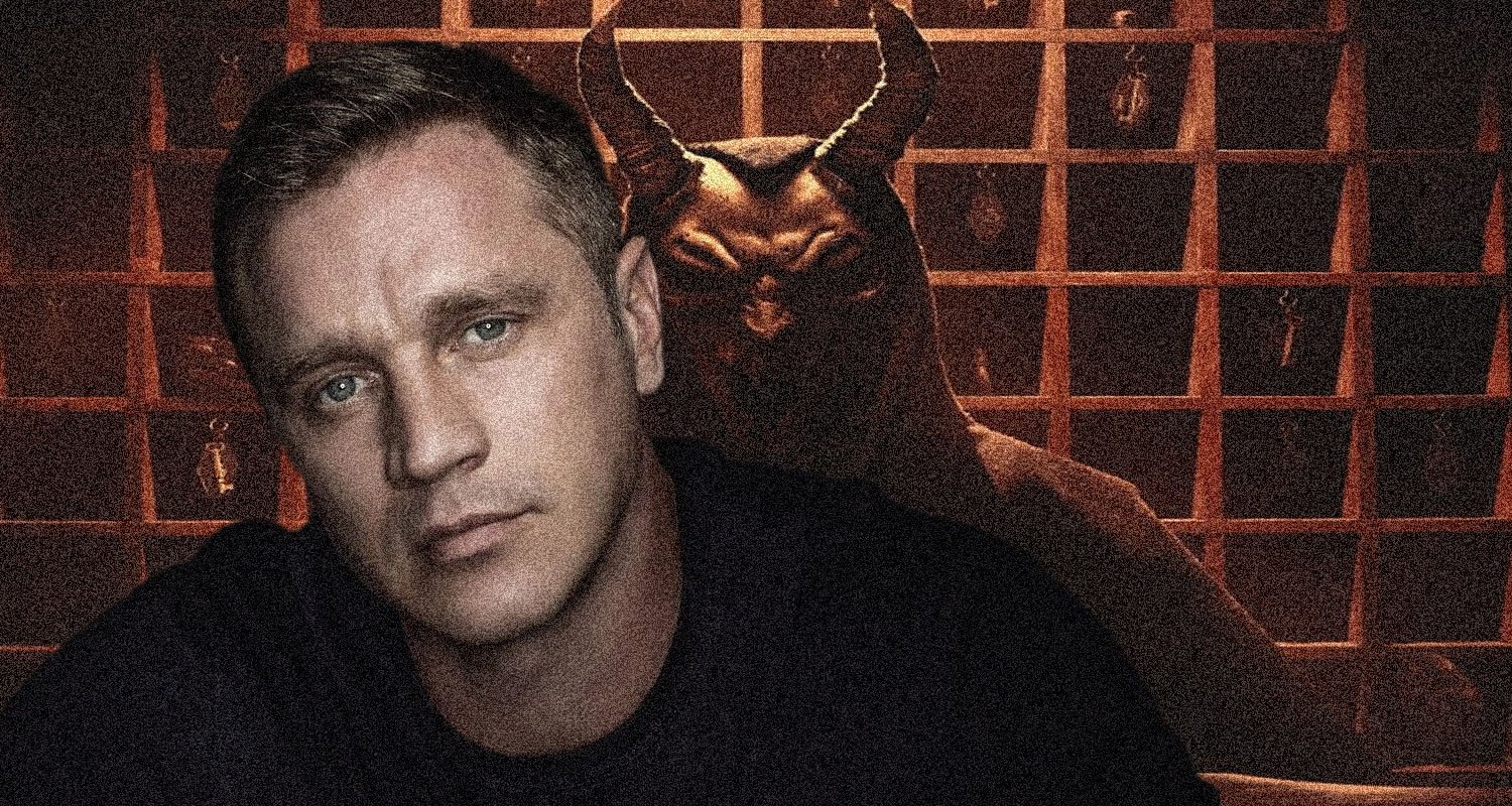 Moody portrait: man in foreground with pale skin, blue eyes, dark shirt; a horned demon figure looms behind him in a dim, grid-patterned background.