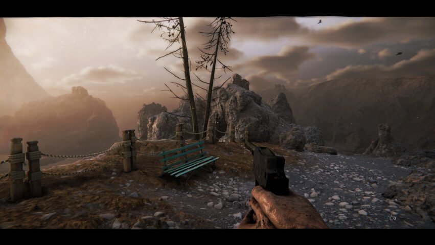 First-person view on a rocky cliff with a handgun, weathered bench, and rope railing overlooking a hazy canyon at sunset.