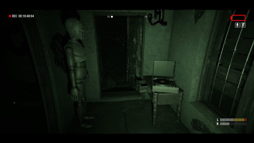 Dimly lit green room with a mannequin standing by a doorway and a vinyl record player on a small table; open dark corridor beyond the door.