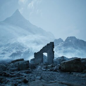 Ruined stone arch sits among rocks with a snow-covered mountain range in a blue-tinted, misty landscape.