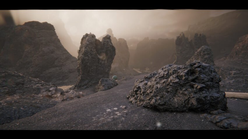Rugged volcanic landscape with jagged rock formations and a small green ball resting on gravel foreground.